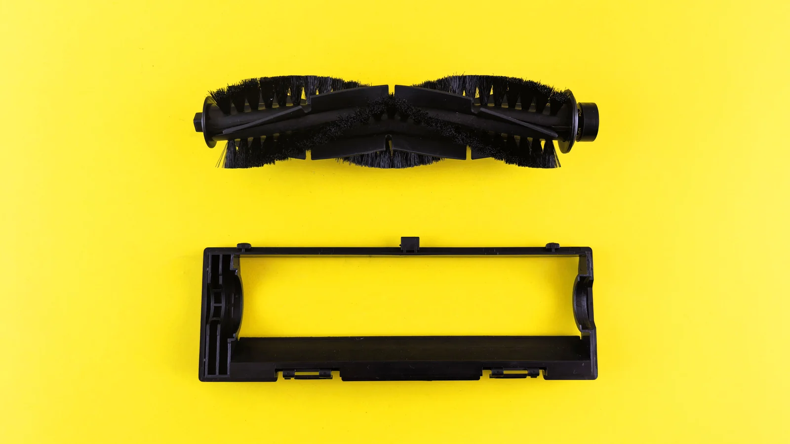 Black vacuum brush roller and rectangular frame on a yellow background.