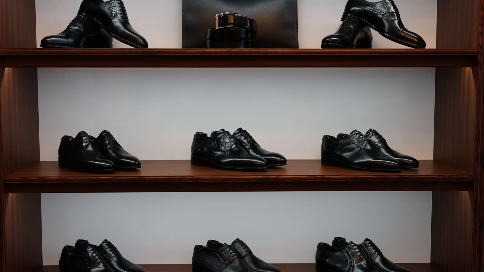 Illustrative stock image of black shoes and boots displayed on wooden shelves.