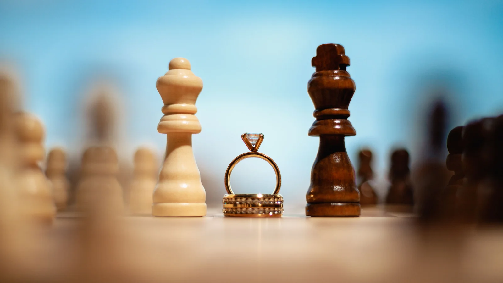 Gold-colored rings arranged between light and dark chess pieces.